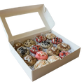 An assortment of decorated cookies arranged on a dark cooling rack, including chocolate chip cookies, pink frosted cookies, and drizzled chocolate and white icing cookies.